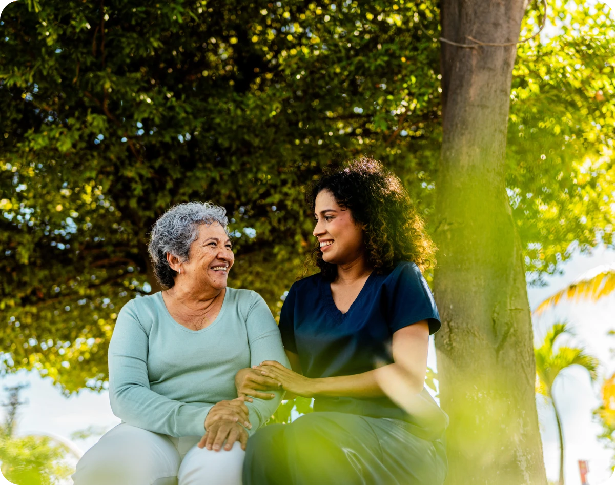 Elderly woman and caregiver smiling outdoors